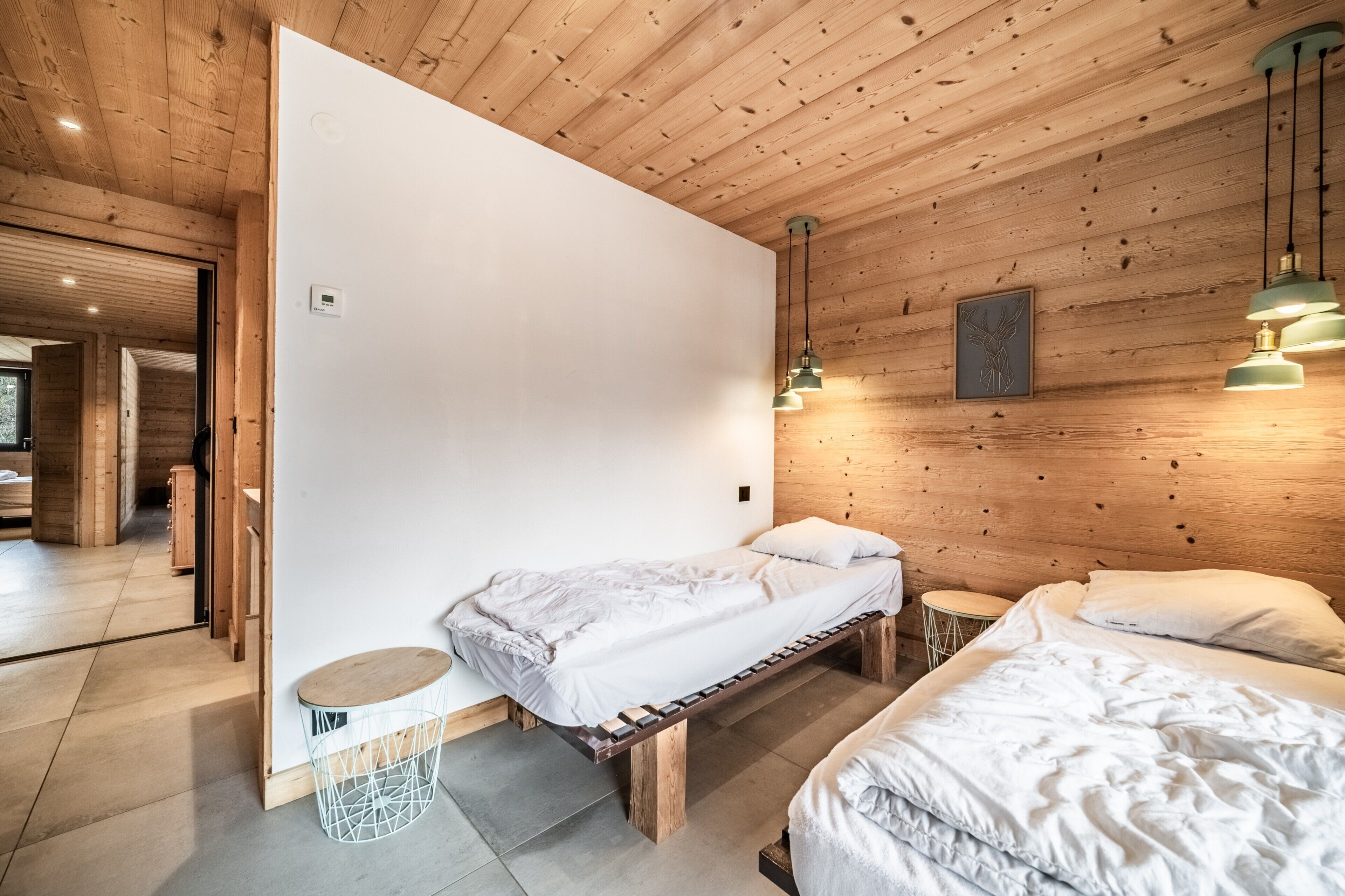 A wooden-paneled room with a bed, bedside table, and a small round table.