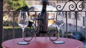Une table avec deux verres à vin et une bouteille, le tout placé sur fond de paysage montagneux.