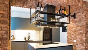 Une cuisine moderne avec un mur en briques, un four encastré et un meuble à bouteilles de vin au-dessus du plan de travail.