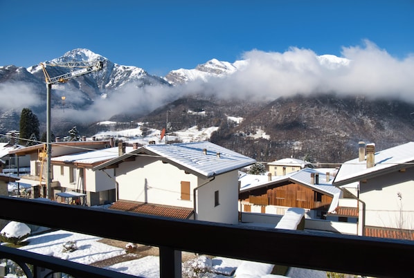 A residential area with snow-covered roofs and houses, a crane, and mountains in the background.