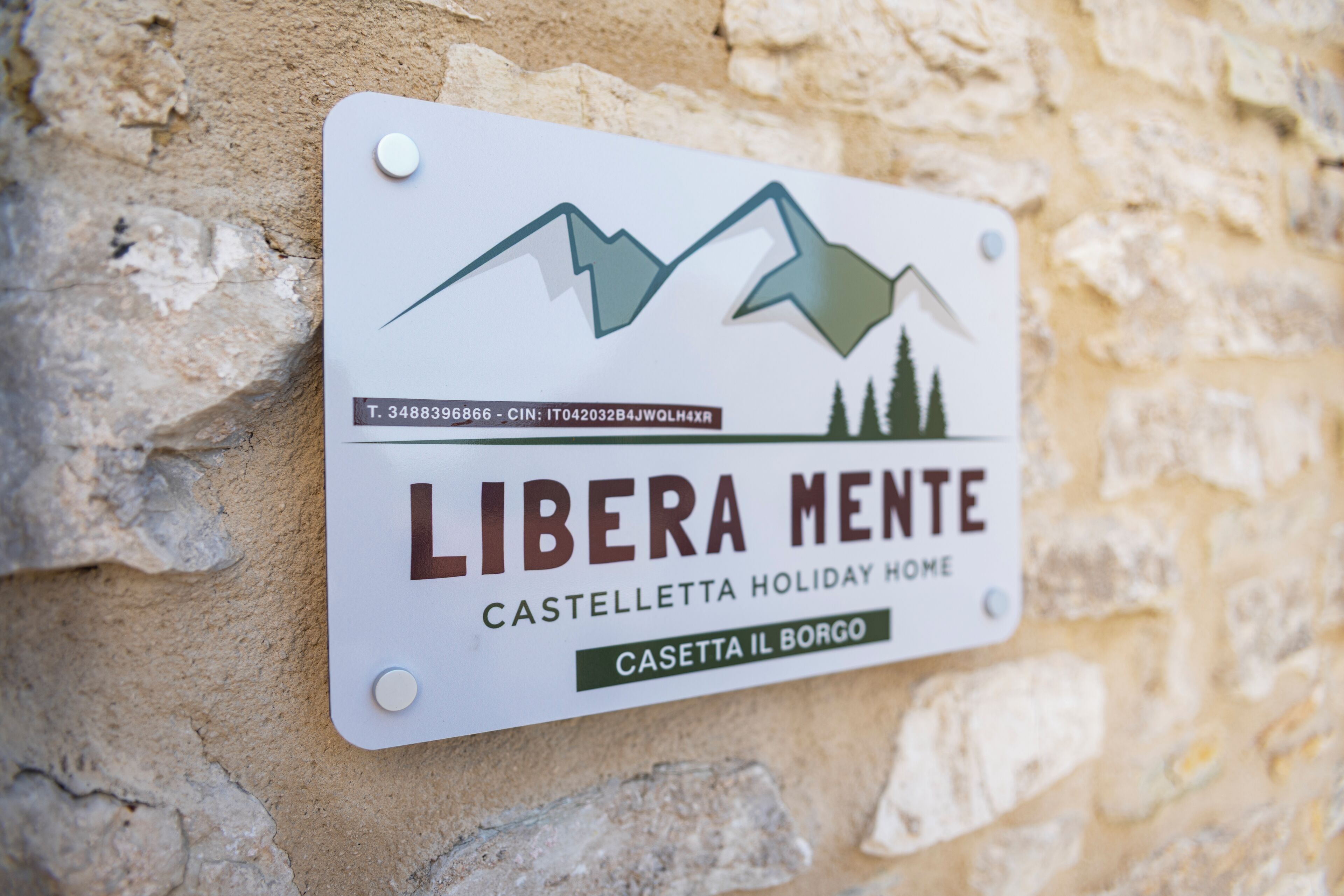 Une enseigne indiquant « LIBERA MENTE CASTELLETTA, MAISON DE VACANCES », avec un motif représentant une montagne et un arbre.