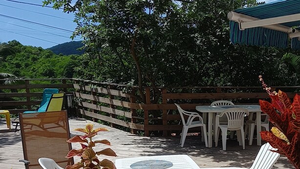 Une terrasse extérieure aménagée avec du mobilier en bois, notamment des chaises et une table, et entourée d’une clôture en bois.