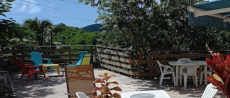 Eine Terrasse im Freien mit Holzmöbeln, darunter Stühle und ein Tisch, umgeben von einem Holzzaun.