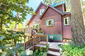 A wooden cabin with a wooden deck, a staircase, and a small porch area. - Secluded 3-bedroom log cabin in  Lake Arrowhead on one acre. (Lake Arrowhead)
