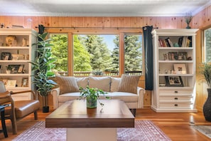 A cozy living room with a sofa, coffee table, and bookshelves. - Secluded 3-bedroom log cabin in  Lake Arrowhead on one acre. (Lake Arrowhead)