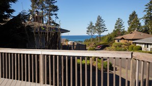 Terraza de madera con vista a una casa y al océano.