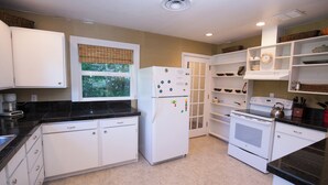 Una cocina con armarios blancos, un refrigerador, un horno y una estufa.