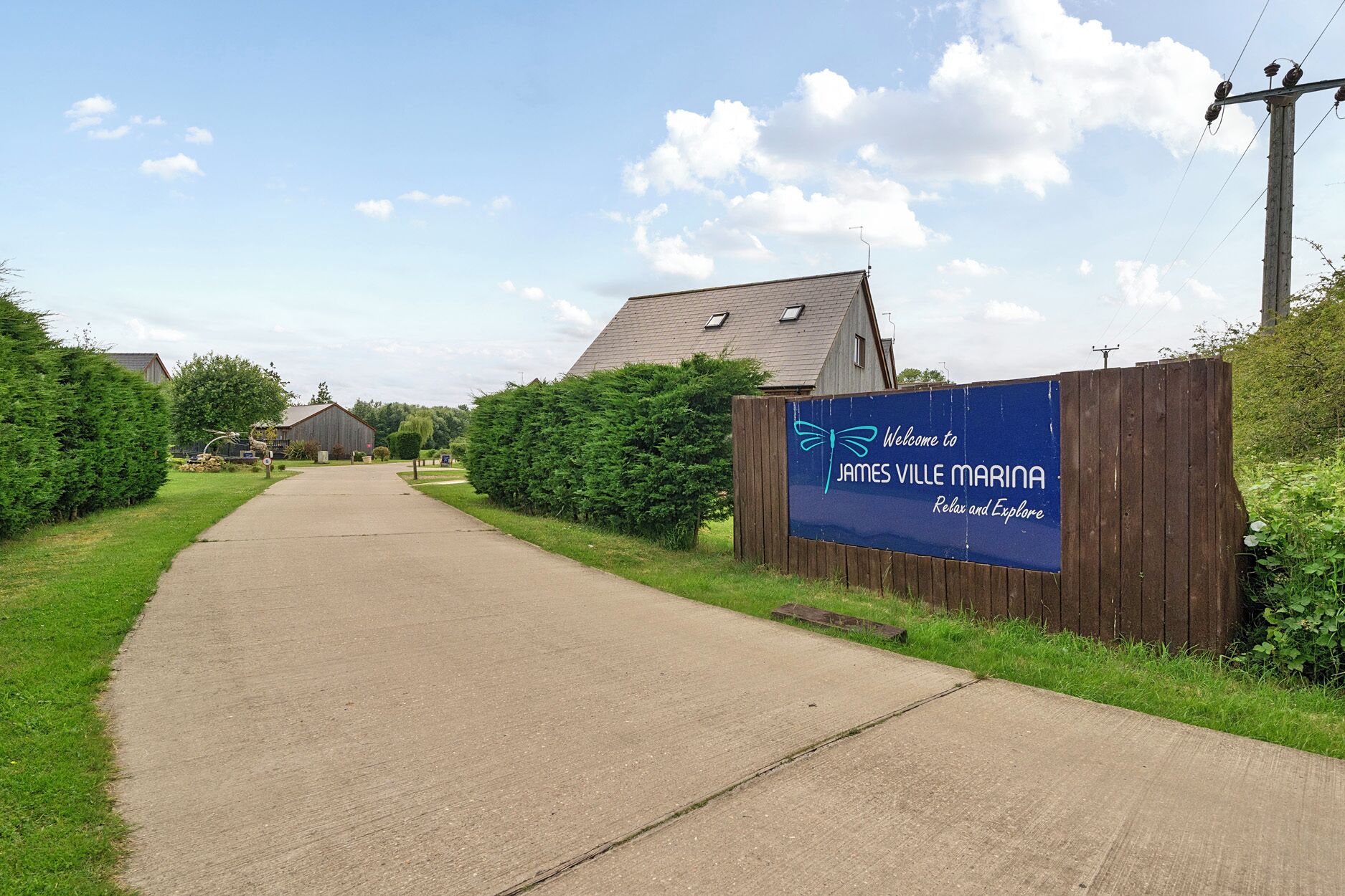 A pathway leading to a building with a sign reading 'Welcome to James Ville Marina.'