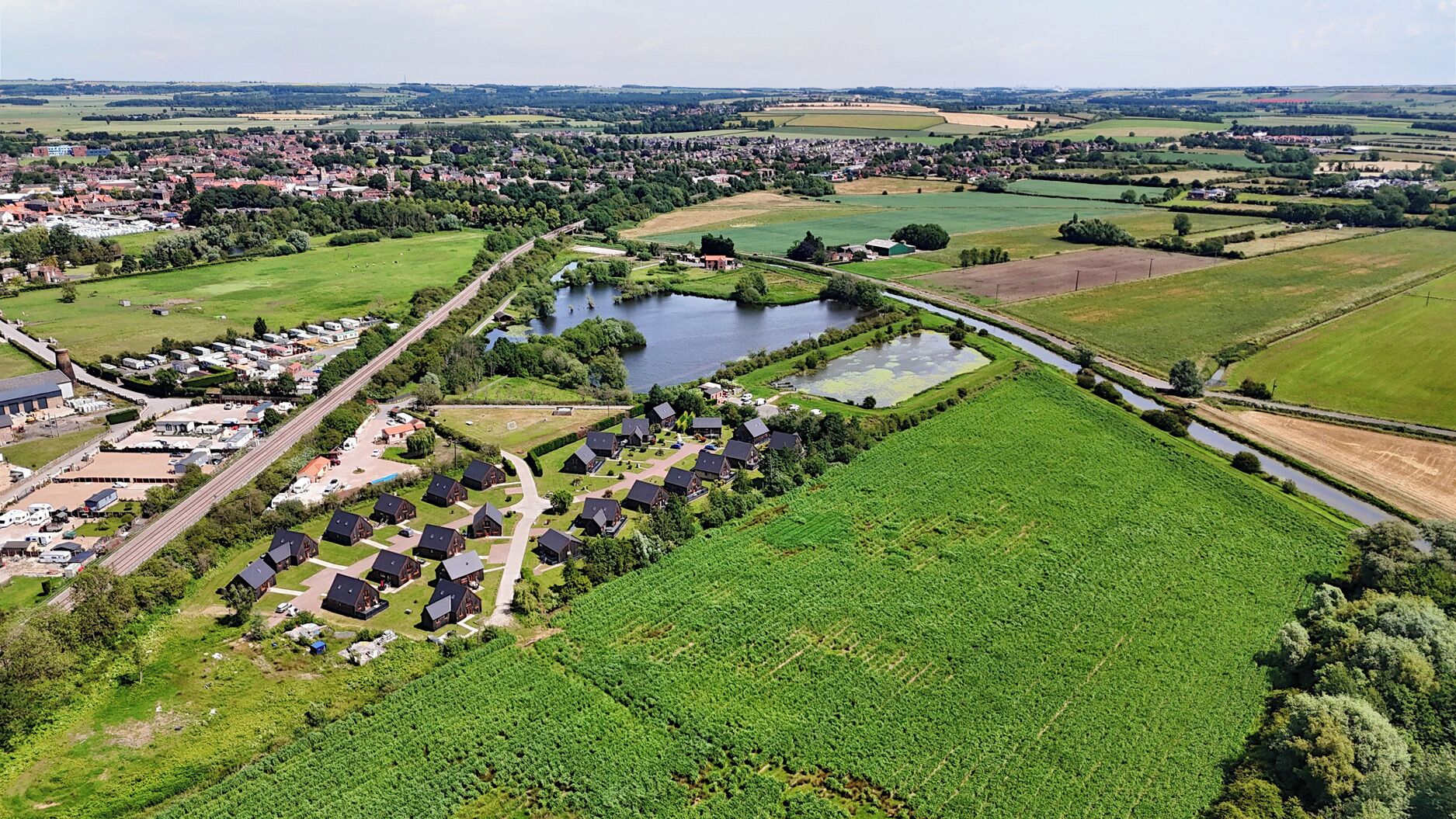 An aerial view of a rural area with a cluster of houses near a lake and fields.