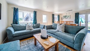 A living room with a sofa set, a coffee table, and a dining area with a table and chairs. - Lodge 22 - Olive (Brigg)