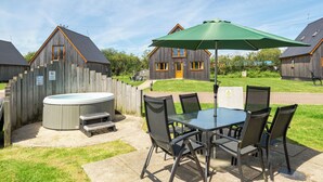 A patio with a hot tub, a table, and chairs. - Lodge 22 - Olive (Brigg)