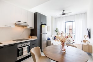A modern kitchen with dark cabinets, a built-in oven, and a round dining table with a vase of flowers. - One bedroom, luxury style and pool view (Punta Cana)