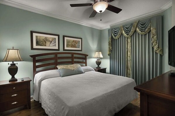 A neatly arranged bedroom with a bed, two bedside tables with lamps, a ceiling fan, and a window with curtains. - Oceanfront Villa | Pool Access | North Myrtle Beach Views (North Myrtle Beach)