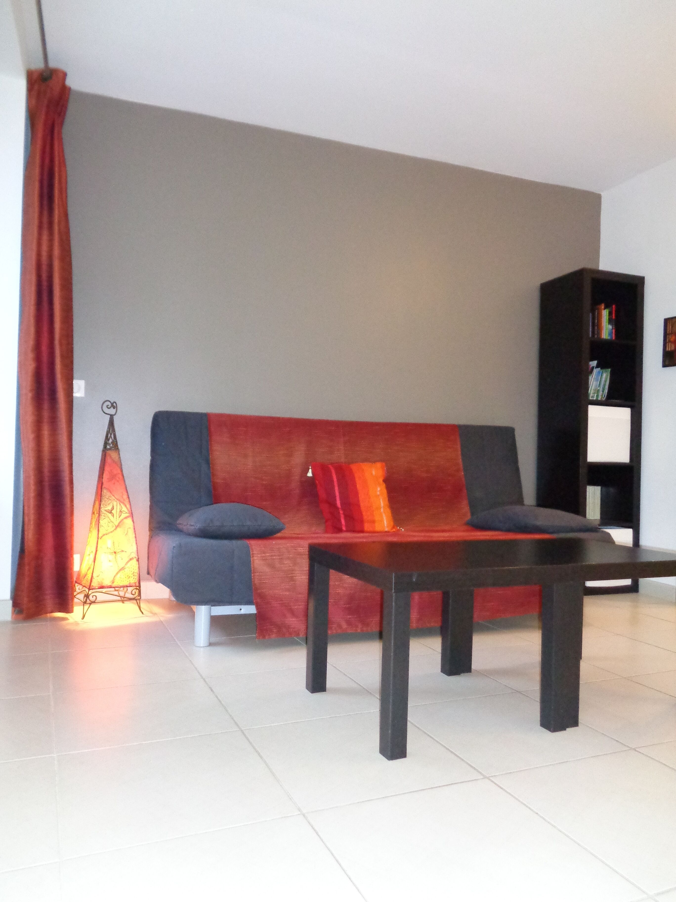 A modern living room with a sofa, a coffee table, a bookshelf, and a floor lamp.