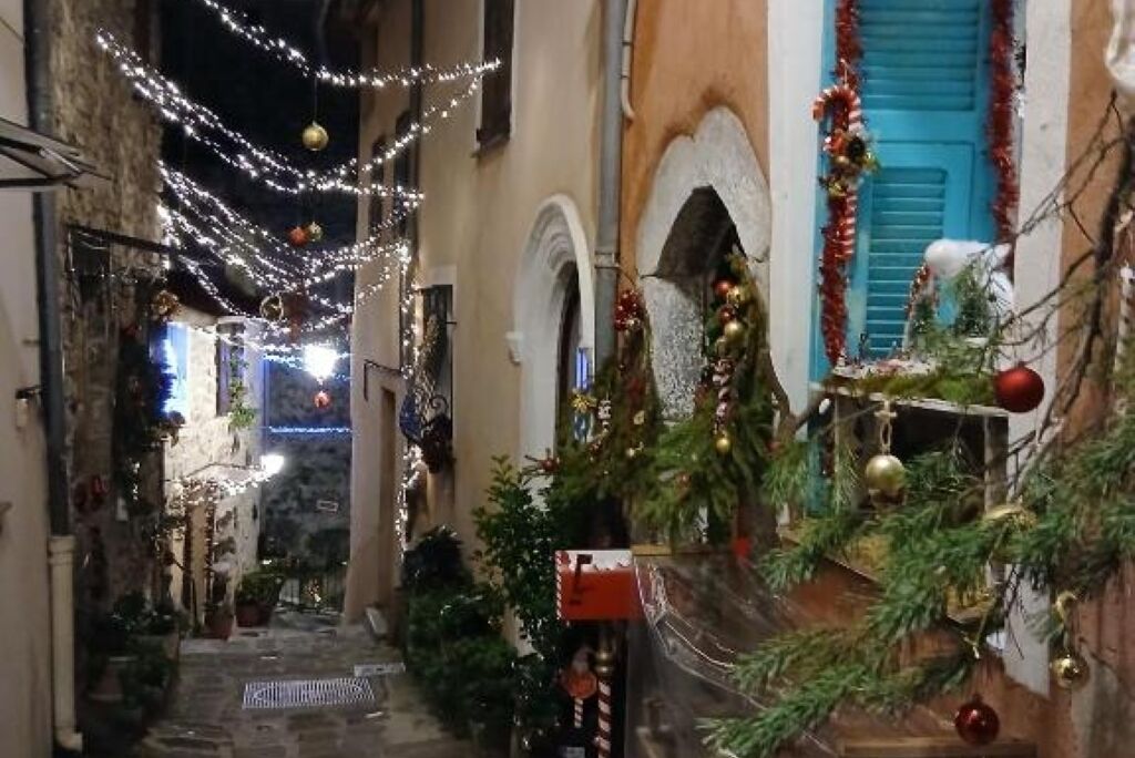 Een smalle straat versierd voor de feestdagen, met lichtslingers en kerstbomen.