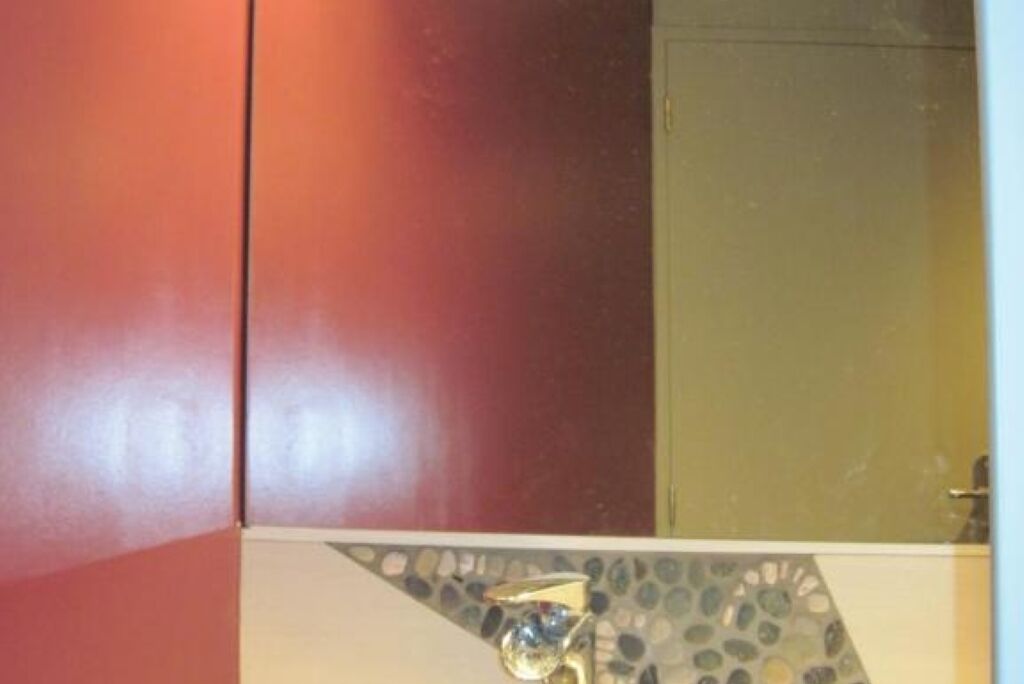 A bathroom with a red wall, a tiled floor, and a shower area.
