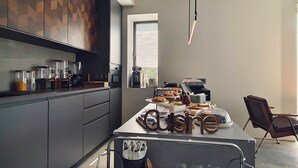 A modern kitchen with grey cabinets, a central island with food items, and a dining area with chairs. - ModernInfluence (Porto)