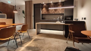 A modern kitchen with a central island, pendant lighting, and a dining area with wooden furniture. - ModernInfluence (Porto)