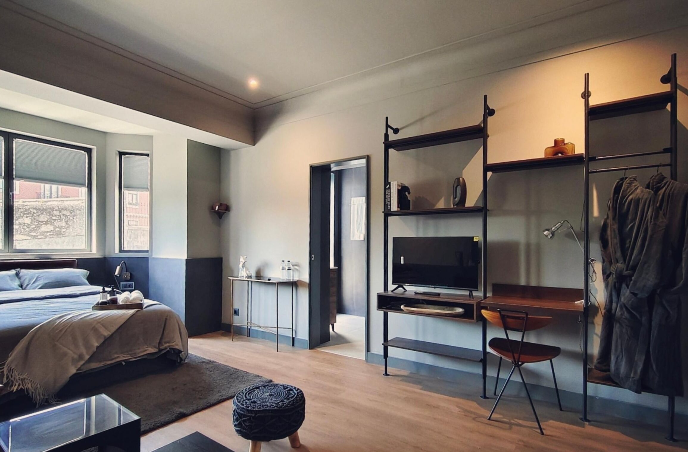 A modern bedroom with a bed, a desk, a chair, and a TV.