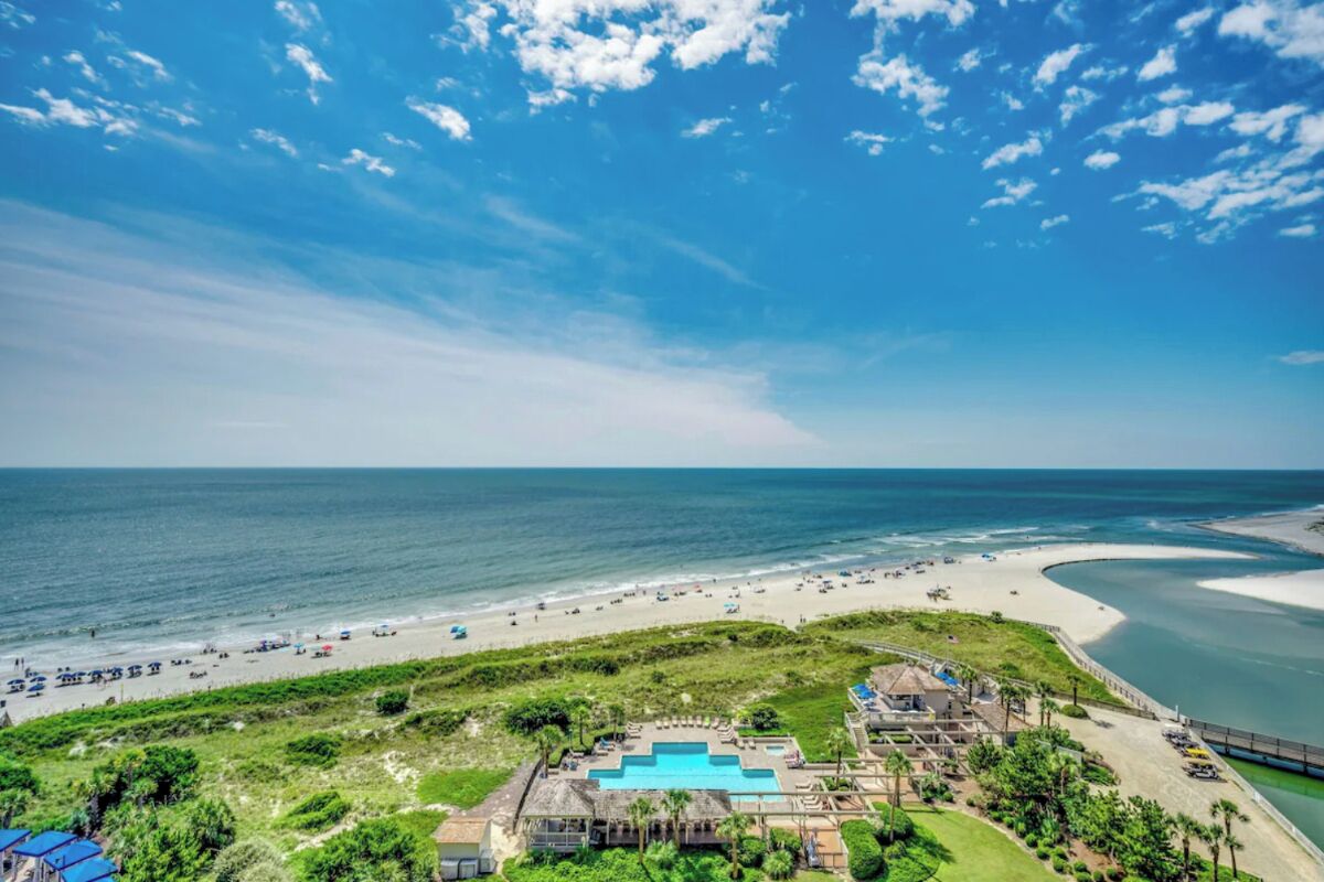A coastal resort with a swimming pool, beach access, and a view of the ocean.