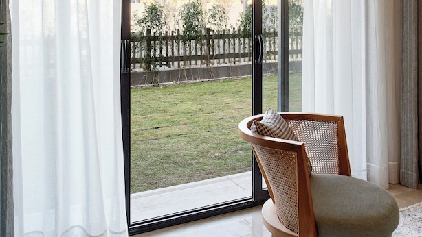 A room with a large sliding glass door leading to a balcony, a wicker chair, and a tiled floor. - Vesta - Luxury Apt - 2BR - CFC (XVI) (New Cairo City)