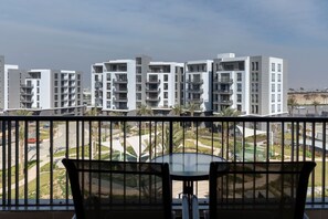 Ein Balkon mit Tisch und Stühlen mit Blick auf ein Wohngebiet mit modernen Gebäuden und einer Straße.