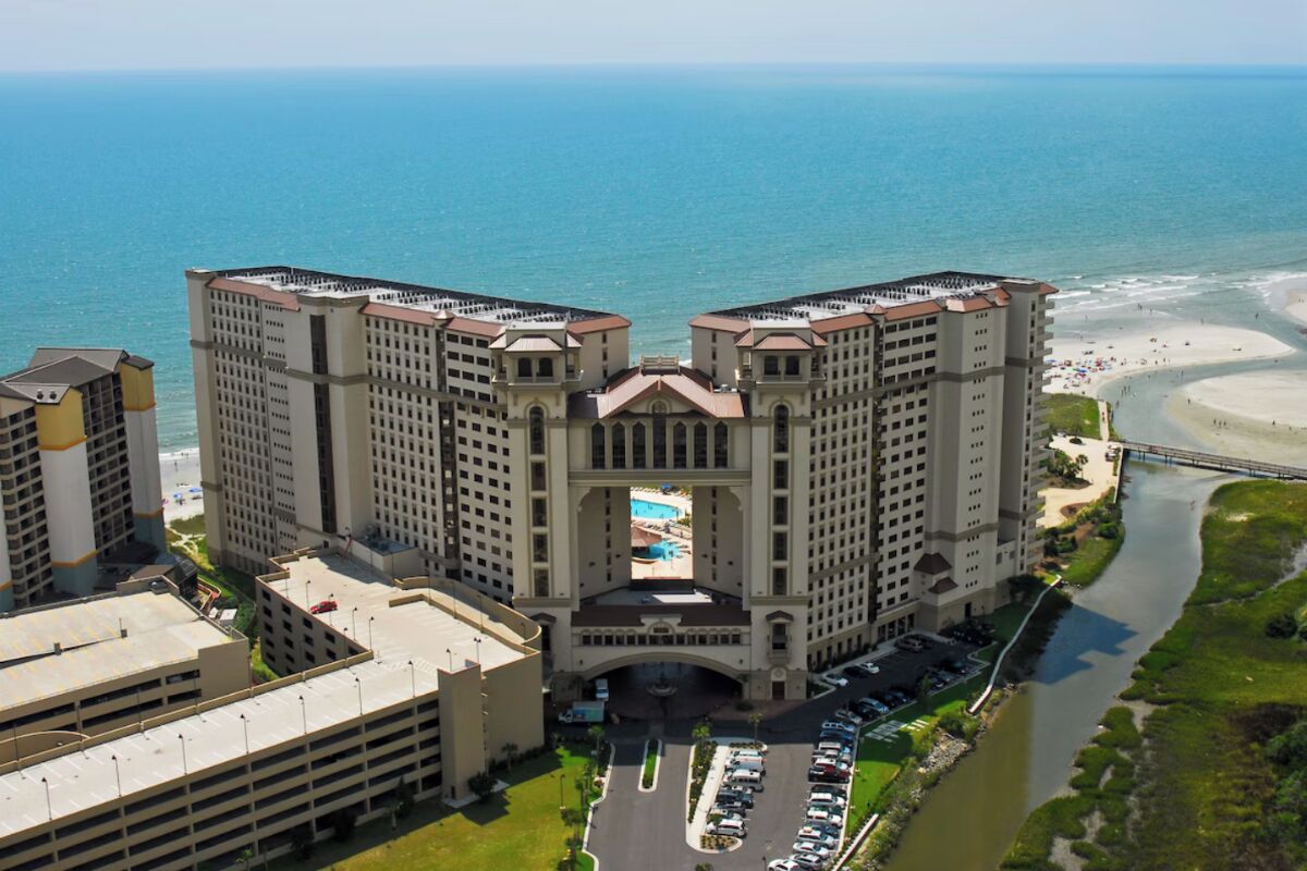 Un hotel moderno con cortile interno, parcheggio e vista sulla spiaggia e sull'oceano.