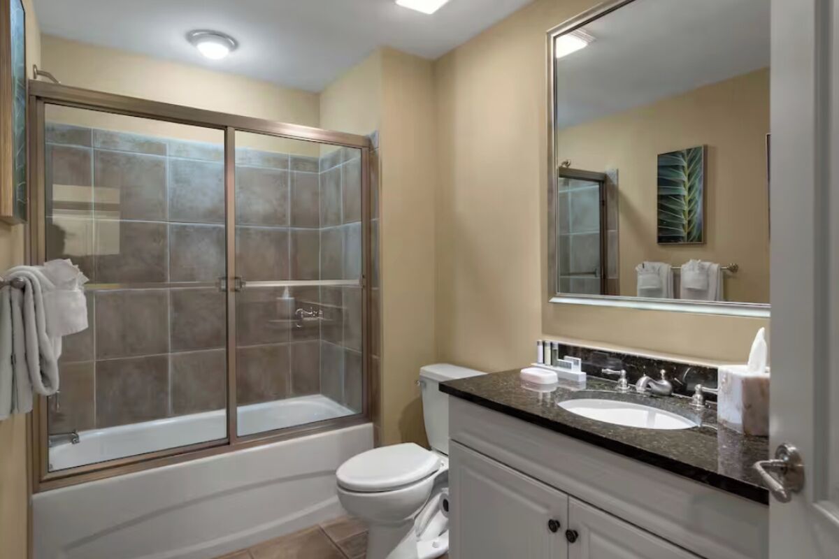 Une salle de bain avec une douche à parois de verre, des toilettes blanches et un meuble-lavabo.