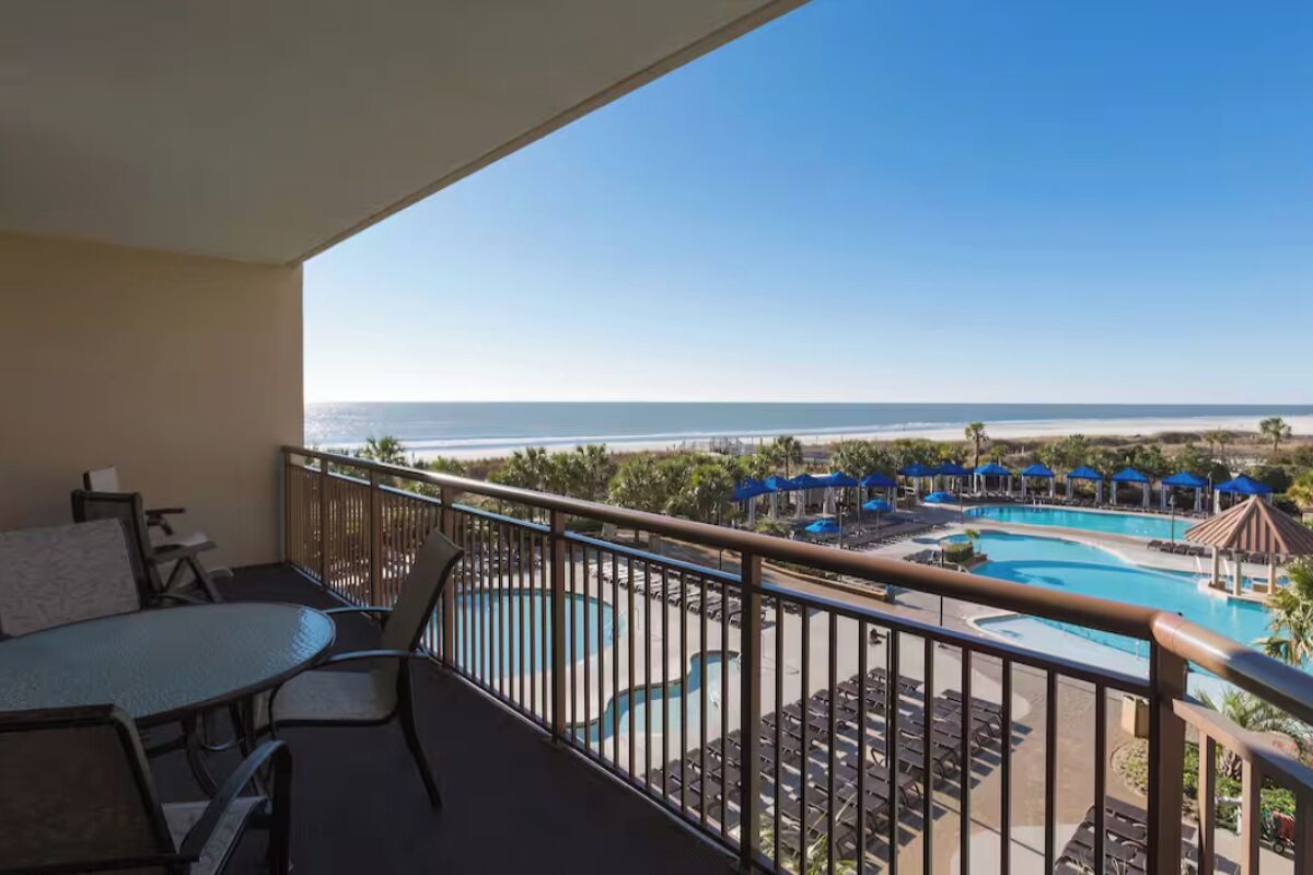 Ein Balkon mit Blick auf Pool und Strand.