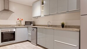 A modern kitchen with grey cabinets, a built-in oven, microwave, and dishwasher. - Vesta - Luxury Apt - 2Br - Cfc (XXXI) (New Cairo City)