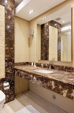 Une salle de bain moderne avec un plan de toilette en marbre, un grand miroir et des toilettes.