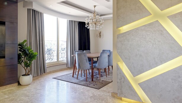 Ein moderner Essbereich mit einer Chandelier, einem Esstisch mit Stühlen und einer Zimmerpflanze.
