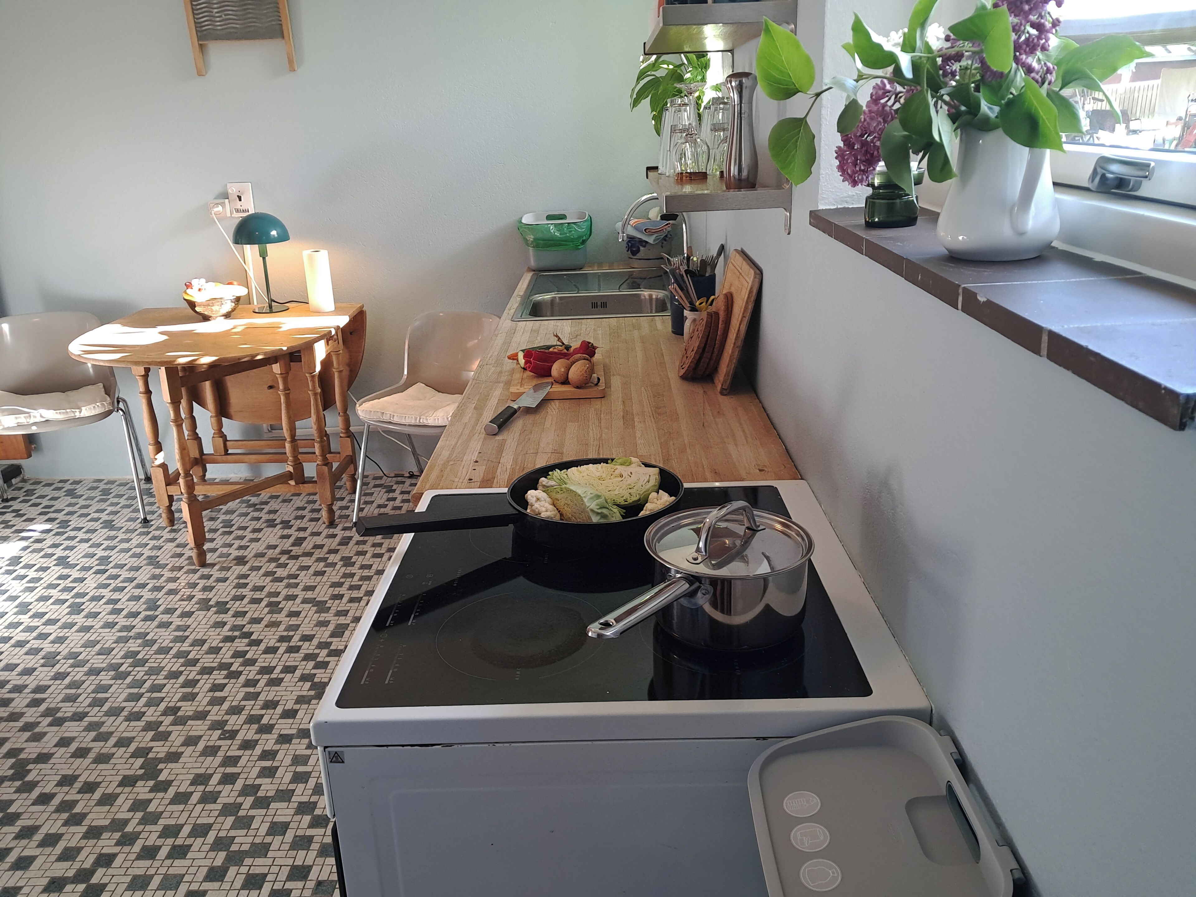 Cuina amb fogó, mànega, taula de fusta i cadires.