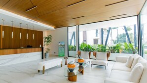Ein moderner Empfangsbereich mit einem Holzbüro, weißen Sofas und einem Glastisch.