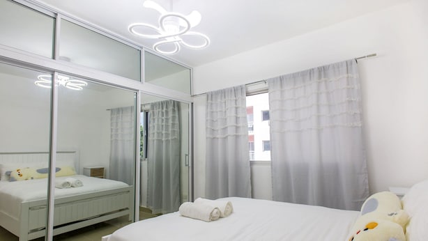Een hotelkamer met een bed, een grote spiegel, een pluche knuffel en een lamp.