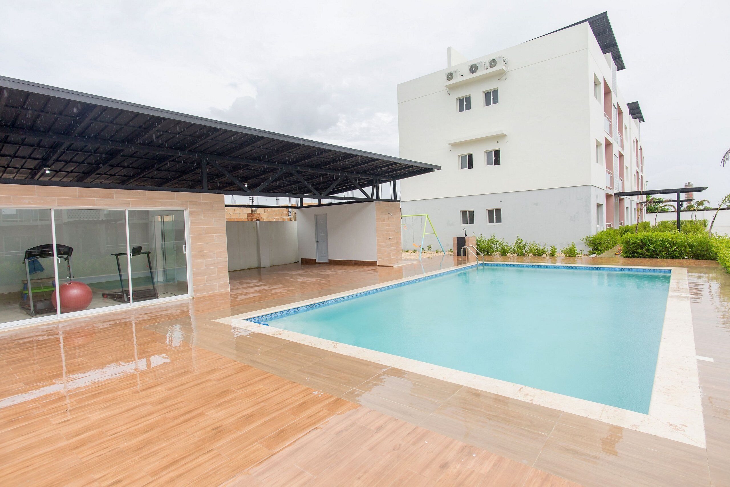 A swimming pool with a covered area and a building in the background.