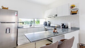 Een moderne keuken met witte kasten, een granieten werkblad en een roestvrijstalen koelkast.