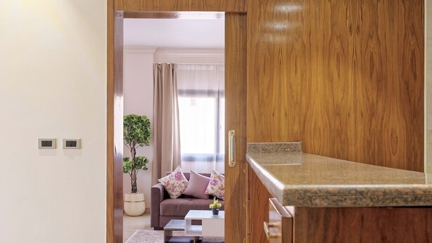 A modern living room with a wooden cabinet, a sofa with cushions, and a potted plant.