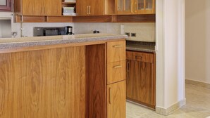 A kitchen with wooden cabinets, a granite countertop, and a microwave.