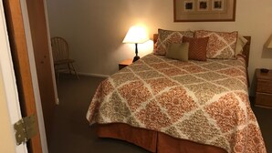Ein Schlafzimmer mit Bett, Nachttisch, Stuhl und einem Bilderrahmen an der Wand.