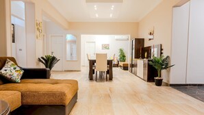 Una sala de estar amplia con un sofá grande, un comedor con mesa y sillas, y una cocina con refrigerador y alacenas.