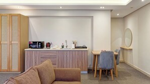 A modern living room with a sofa, a dining area with a table and chairs, a kitchen counter with appliances, and a wardrobe. - VESTA - Luxury Studio - New Cairo (I) (New Cairo City)