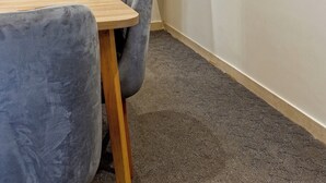 A corner room with a wooden table and a single grey chair. A round mirror hangs on the wall above the table. - VESTA - Luxury Studio - New Cairo (I) (New Cairo City)