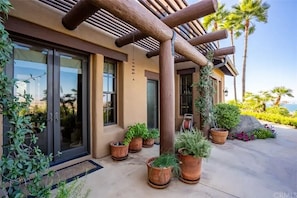 A modern building with a wooden pergola, large windows, and potted plants. - Spanish Mansion - Architectural Delight! (Perris)
