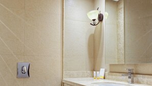 Un baño con inodoro, lavamanos, espejo y aplique de pared.