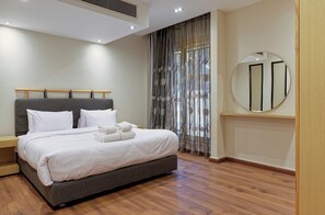 Ein modernes Hotelzimmer mit einem großen Bett, einem runden Spiegel und einem Holzboden.