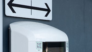 A public charging station with a digital display and two charging ports, labeled "WAAT".