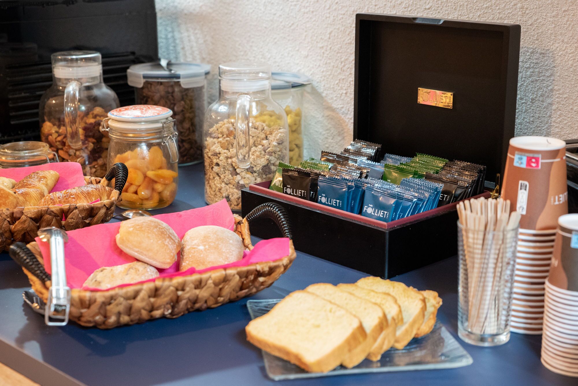 Un tavolo del buffet con diversi cibi, tra cui pasticcini, pane e snack confezionati.