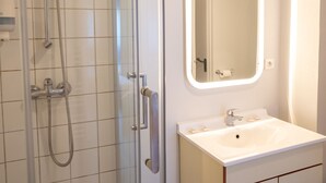 A bathroom with a glass shower enclosure, a white sink with a mirror above it, and a towel rack. - Charmant studio au Cœur de Brest | Près de la Mer (Brest)