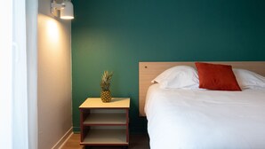 Een hotelkamer met een bed, een nachtkastje, een ananas en een wandlamp.